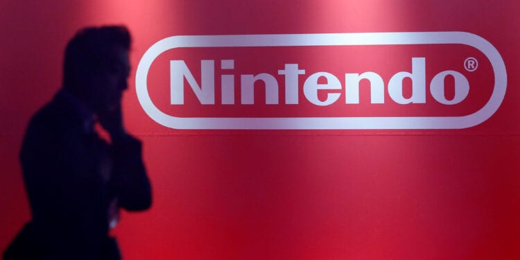 A man stands in front of Nintendo's logo at the presentation ceremony of its new game console Switch in Tokyo