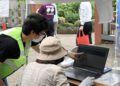 Estudante orienta uma idosa durante evento sobre crimes cibernéticos em Saitama. Reprodução/Jornal Asahi.