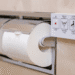 Close-up of a bathroom toilet area showing a wall control panel beside a toilet paper roll holder with a white roll.