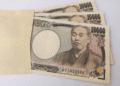 Several 10,000 yen banknotes partially tucked into a light brown envelope.