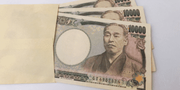 Several 10,000 yen banknotes partially tucked into a light brown envelope.