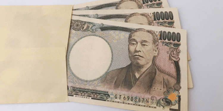 Several 10,000 yen banknotes partially tucked into a light brown envelope.