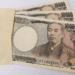 Several 10,000 yen banknotes partially tucked into a light brown envelope.