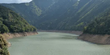 Calm river or reservoir winding through a forested mountain valley with steep slopes on either side.