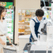Smiling woman with a shopping cart at the checkout while a cashier in a blue apron scans items at a grocery store register.