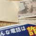 Anti-fraud poster in Japanese warning about scam calls, with a stack of cash visible beside an envelope.