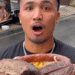 Young man with a shocked expression holding a massive smoked meat roast outdoors, with a food truck in the background.
