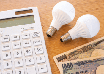 Calculator with two white bulbs and 1,000-yen banknotes on a wooden desk.