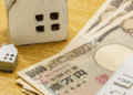 Money and house models on a wooden desk with a calculator, suggesting mortgage or real estate financing.