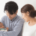 Young couple gently cradle their newborn baby, looking at the infant with affection in a bright room.