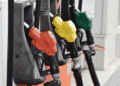 Close-up of several fuel nozzle handles in red, yellow, and green at a gas pump station.