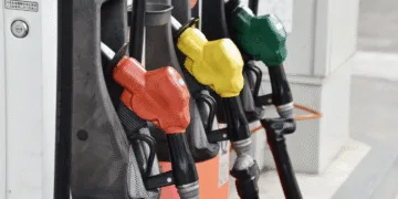 Close-up of several fuel nozzle handles in red, yellow, and green at a gas pump station.