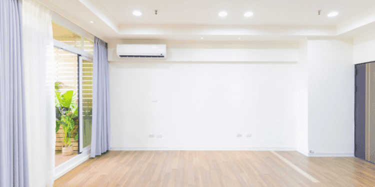 Bright empty living room with wood floor, white walls, recessed lighting, and a sliding glass door with purple curtains.