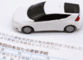 Instituto propõe alta de 144 no seguro automotivo no Japão a maior já registrada - ThingsOut White toy car resting on a Japanese vehicle license renewal document.