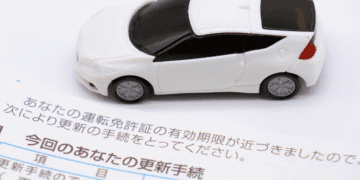 Instituto propõe alta de 144 no seguro automotivo no Japão a maior já registrada - ThingsOut White toy car resting on a Japanese vehicle license renewal document.