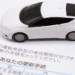 White toy car resting on a Japanese vehicle license renewal document.