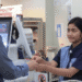 Cashier in a blue uniform hands a plastic bag to a customer at the checkout counter.