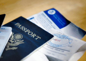 Blue US passport with embossed seal on a wooden table beside travel documents and tickets.