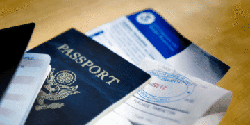 Novas restrições a estrangeiros podem prejudicar a imagem global do Japão - ThingsOut Blue US passport with embossed seal on a wooden table beside travel documents and tickets.