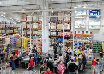 Busy supermarket checkout area with many customers and cashiers at registers.