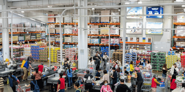 Busy supermarket checkout area with many customers and cashiers at registers.