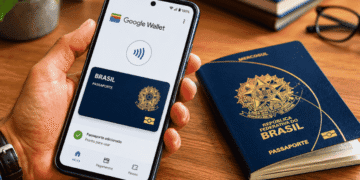 Passaporte no celular Google libera função para brasileiros e amplia uso da Wallet - ThingsOut Hand holding a phone displaying Google Wallet with a Brazilian passport card, beside a real Brazil passport on a wooden desk.