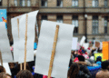 Crowd of protesters holding blank white placards on wooden sticks at a demonstration in the city.