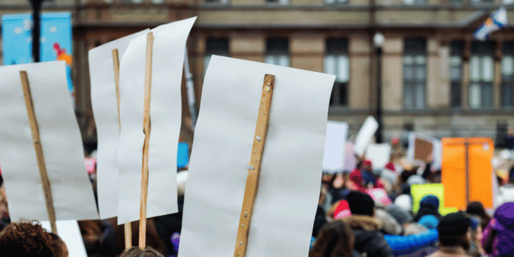 Crowd of protesters holding blank white placards on wooden sticks at a demonstration in the city.