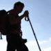 Shizuoka avalia limitar escalada do Monte Fuji fora de temporada após série de resgates - ThingsOut Silhouette of a hiker with a red backpack and trekking pole against a bright blue sky at daytime.
