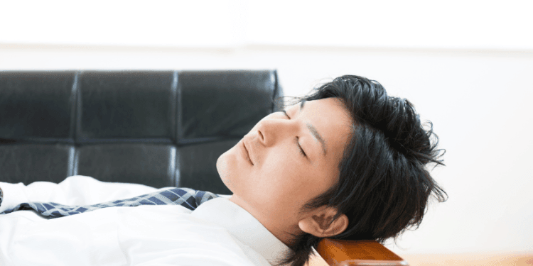 Empresas no Japão estão criando salas de cochilo para seus funcionários - ThingsOut Man in a white shirt and tie resting with his head on an armchair, eyes closed.