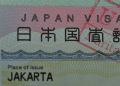 Estrangeiros querem seguir no Japão mas renda e custo de vida mudam planos de permanência - ThingsOut Close-up of a Japan visa card showing 'JAPAN VISA' and 'Place of issue JAKARTA' visible behind a decorative background.