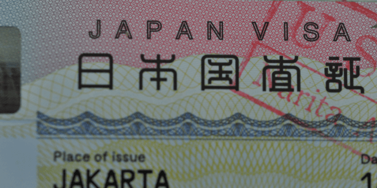 Estrangeiros querem seguir no Japão mas renda e custo de vida mudam planos de permanência - ThingsOut Close-up of a Japan visa card showing 'JAPAN VISA' and 'Place of issue JAKARTA' visible behind a decorative background.