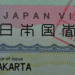 Close-up of a Japan visa card showing 'JAPAN VISA' and 'Place of issue JAKARTA' visible behind a decorative background.