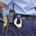 Police officer's waist area with a radio and handcuffs clipped to the belt