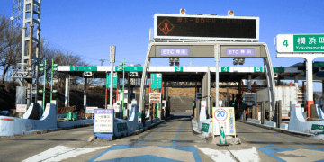 Japão abre campanha para instalar ETC com desconto de até ¥10 mil mas há regras e prazo curto - ThingsOut Highway toll plaza in Japan with multiple ETC lanes and green signs; digital board overhead and a 20 km/h speed limit sign visible in the foreground.