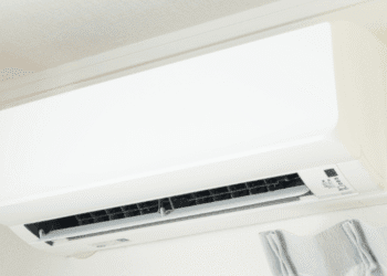 White wall-mounted air conditioner unit with its front panel closed and vent opening visible on the lower front edge.