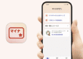MyNavi app icon beside a hand-held phone displaying the app's Japanese login screen.