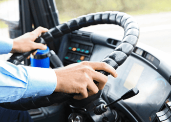 Close-up of hands gripping the steering wheel inside a truck cab.
