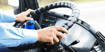 Close-up of hands gripping the steering wheel inside a truck cab.