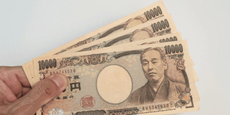 Salário mínimo em Aichi pode subir novamente primeira reunião sobre reajuste é realizada - ThingsOut Hand holding a fan of Japanese 10,000 yen banknotes featuring Yukichi Fukuzawa.