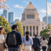 Japans Diet Flag and Diverse Residents - ThingsOut Diverse group of professionals walking toward a grand government building framed by cherry blossoms and a waving Japanese flag on the right.
