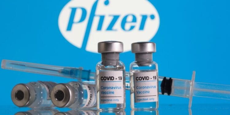 Frascos rotulados como de vacina contra Covid-19 em frente ao logo da Pfizer em foto de ilustração