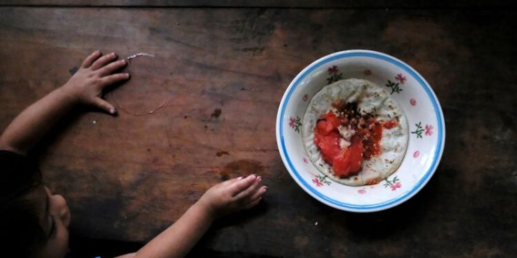 Criança de 1 ano e 10 meses tenta alcançar prato de comida em Palmilla, na Guatemala