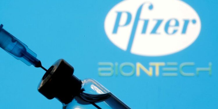 Frasco e seringa em frente aos logos da Pfizer e da BioNTech em foto de ilustração