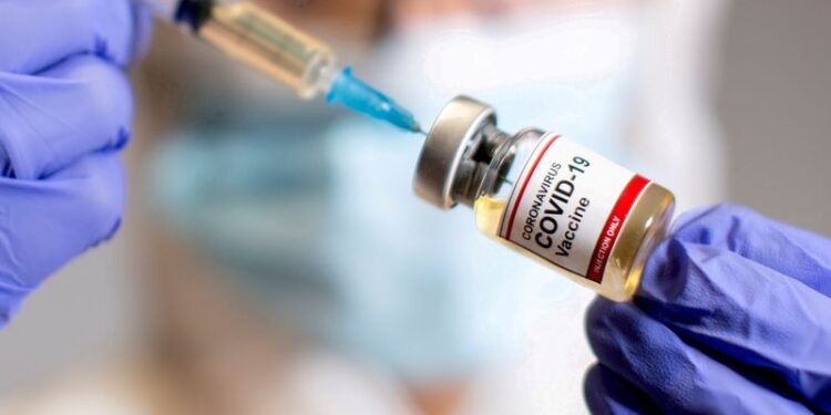 FILE PHOTO: FILE PHOTO: FILE PHOTO: A woman holds a medical syringe and a small bottle labelled "Coronavirus COVID-19 Vaccine