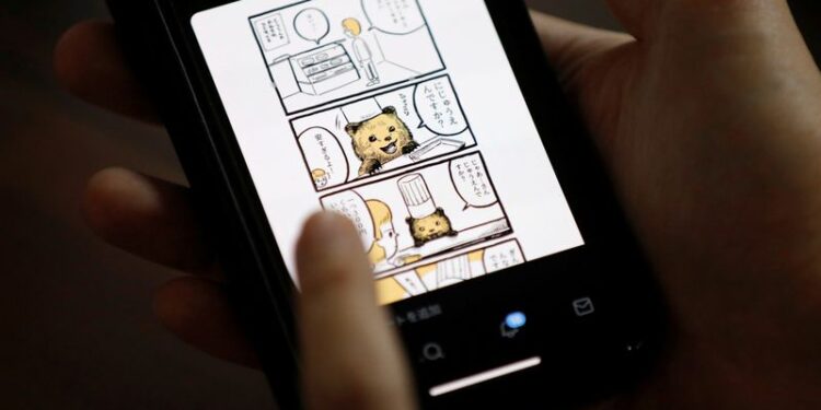 Japanese manga artist Kamentotsu shows his his four-panel strip comic 'Koguma's Cake Shop' on his smartphone at his workspace in Tokyo