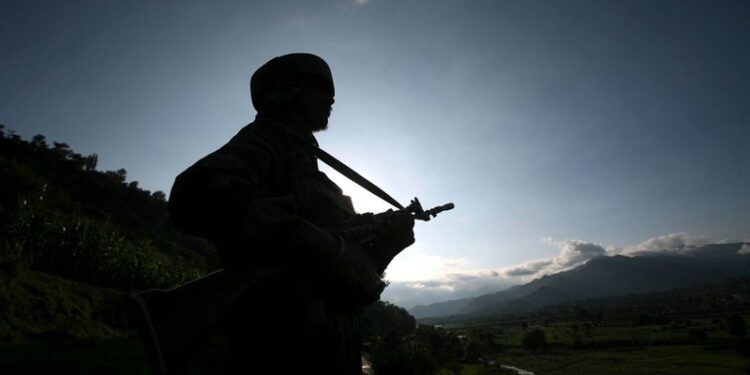 An Indian army soldier stands guard while patrolling near the Line of Control, a ceasefire line dividing Kashmir between India and Pakistan, in Poonch